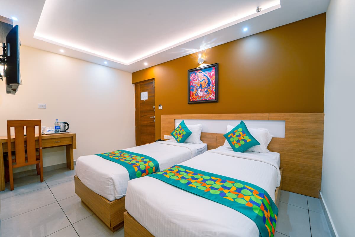A hotel room with two beds, a desk, and a chair.