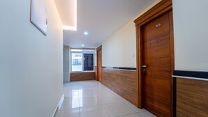 A hallway with a wooden door labeled "102," a window with blinds, and a framed picture on the wall. - Treebo Sree Varshavilas Regency, 500 Mtrs From Guruvayoor Temple (Chavakkad)
