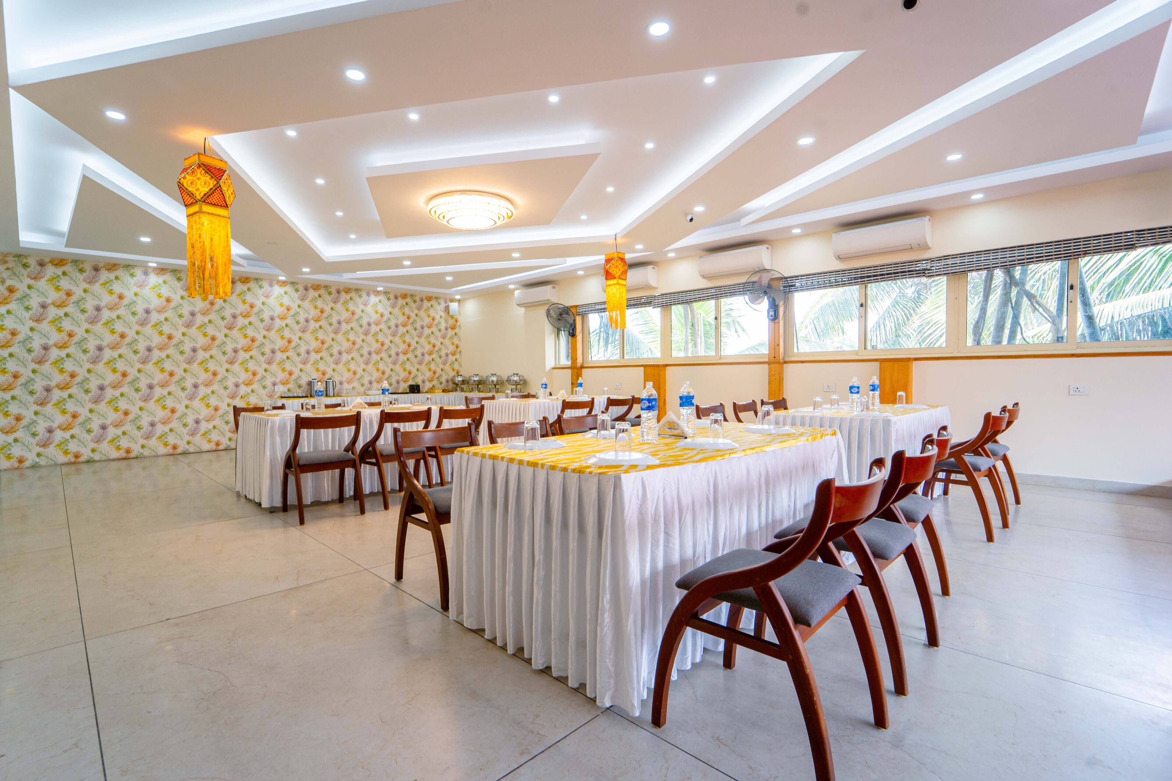 Un vaste espace dédié à la salle à manger, avec plusieurs tables rondes, chacune agrémentée de chaises et recouverte de nappes.