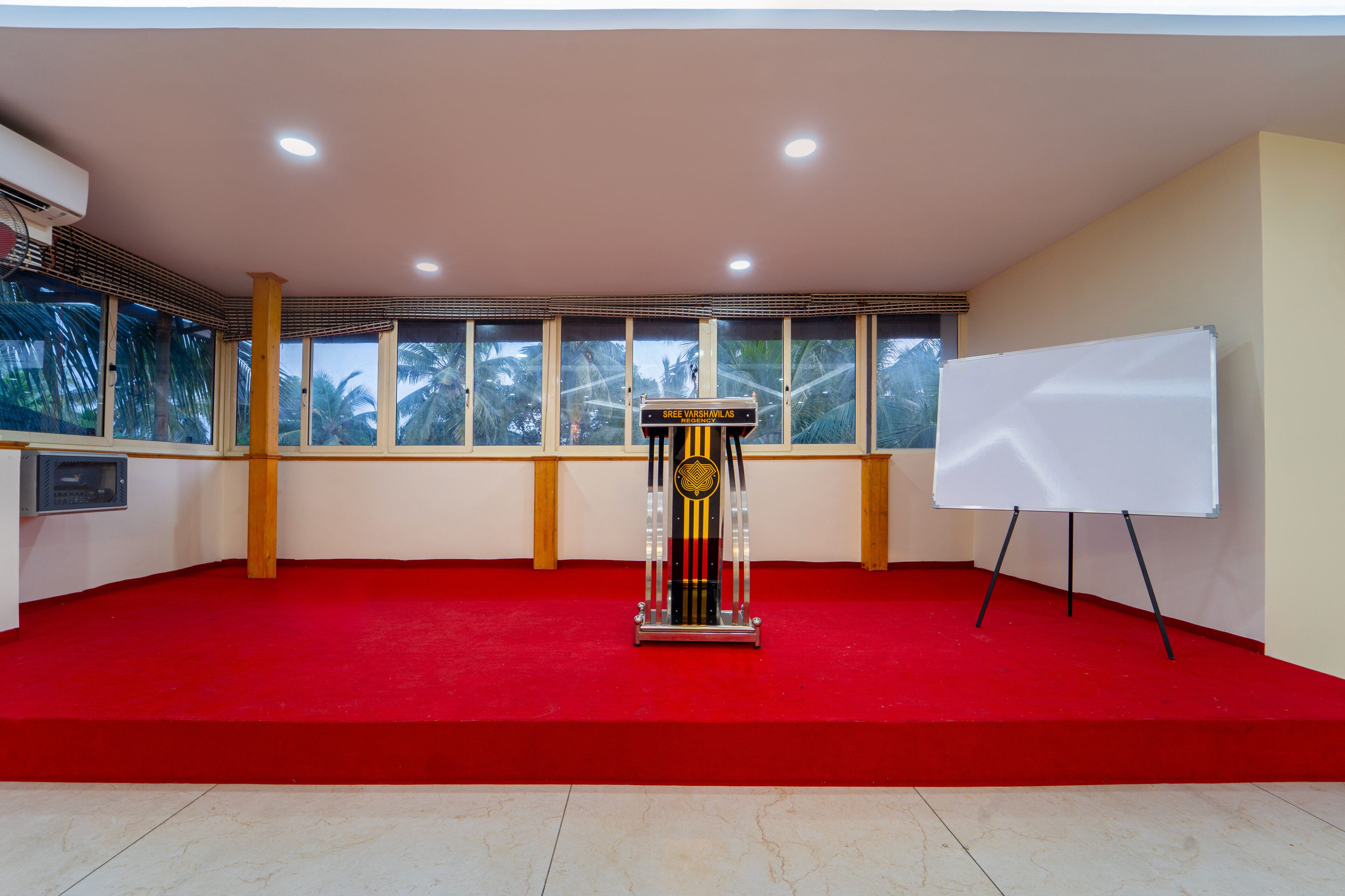 A conference room with a podium, a whiteboard, and large windows with a view of palm trees.
