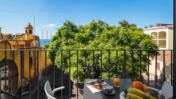 A balcony with a table set for breakfast, overlooking a cityscape and the sea. - The Fort of Old Town 1 by Our Madeira (Funchal)