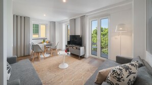 A modern living room with a grey sofa, a dining table with chairs, a flat-screen TV, and a balcony with a railing. - The Fort of Old Town 1 by Our Madeira (Funchal)