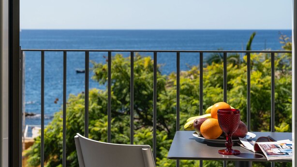 Un balcon avec une table préparée pour le petit-déjeuner, donnant sur la mer.