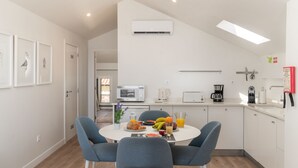 A modern kitchen with white cabinets, a microwave, a kettle, and a coffee maker. There is a dining table with chairs and a fruit bowl. - The Fort of Old Town 3 by Our Madeira (Funchal)