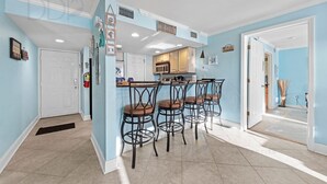 Una cocina con barra, una puerta blanca y un pasillo que conduce a otra habitación.