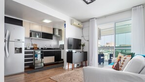 Een moderne keuken met een koelkast, magnetron, oven en een flatscreen televisie.