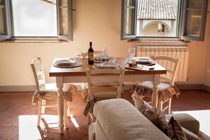 A dining area with a table set for four, including plates, glasses, and a bottle of wine. There are two chairs with checkered cloths, and a radiator is visible in the background. - RIDOLFO HAUS - Apartment in San Miniato (San Miniato)