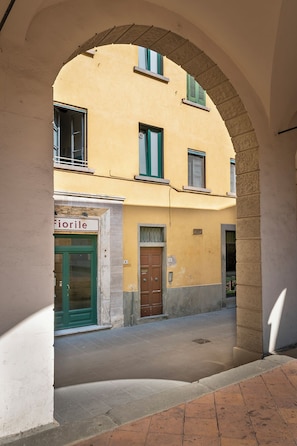 An arched passageway with a building featuring a green door and a sign that reads 'Florile.' - RIDOLFO HOUSE - Apartment in San Miniato (San Miniato)