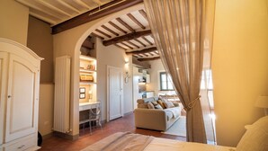 A bedroom with a large bed, a desk, and a sofa. There is a wardrobe and a window with curtains. - RIDOLFO HOUSE - Apartment in San Miniato (San Miniato)
