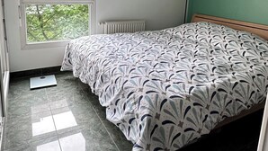 Ein Schlafzimmer mit einem Bett, einem Fenster, einer Heizung und einer grünen Wand.