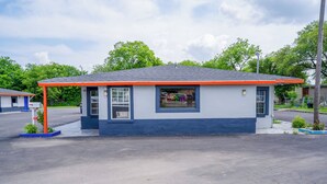 A small, single-story building with a blue and white exterior, a red roof, and a 'OPEN' sign. - Alamo Oasis Inn And Suites By Oyo San Antonio (San Antonio)