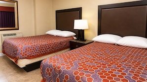 A hotel room with two beds, a nightstand with a lamp, a mirror, and a wall-mounted air conditioning unit. - Sai Park Motel (Lancaster)