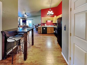 Una cocina con armarios de madera, un refrigerador negro y una zona de comedor con una mesa y sillas.
