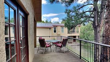 A wooden deck with a table and chairs, a railing, and a view of houses and trees.