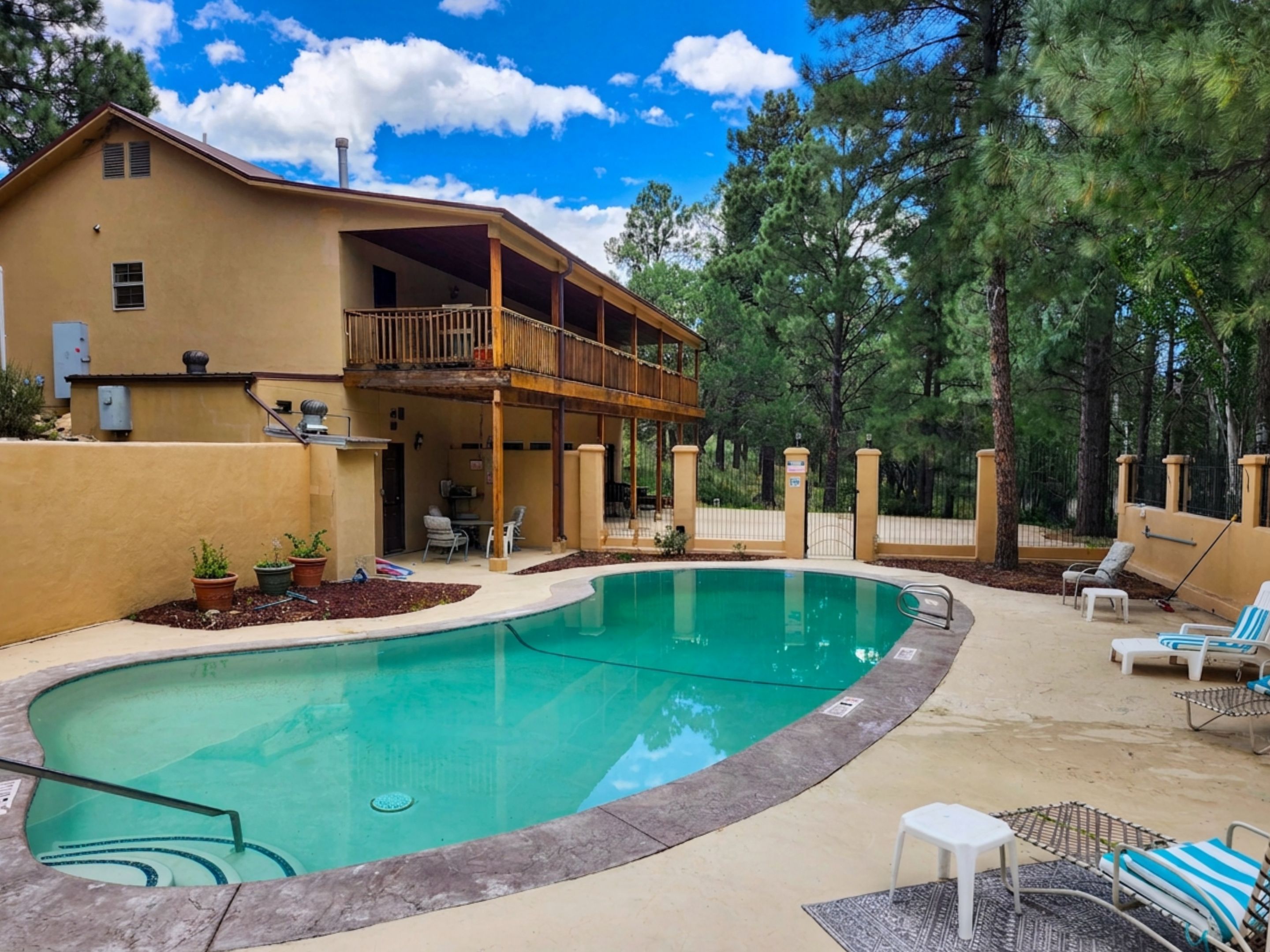 A two-story house with a swimming pool, outdoor furniture, and a covered patio area.