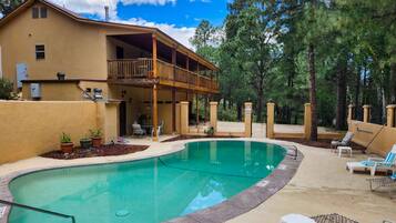 A two-story house with a swimming pool, outdoor furniture, and a covered patio area.