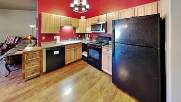 A compact kitchen with wooden cabinets, a black refrigerator, a microwave, and a stove.