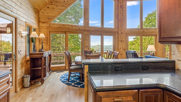 A spacious kitchen with large windows, wooden cabinetry, and a central island.