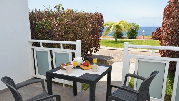 A balcony with a table set for breakfast, two chairs, and a view of the sea. - Apt. El Guirre Nº 8 - bajo (Valle Gran Rey)