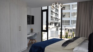A modern bedroom with a large bed, a desk, and a wardrobe. - Harmony Luxury Apartments  (Quito)