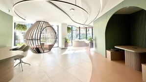 A modern office space with curved ceiling lights, a spherical seating area, and a reception desk. - Harmony Luxury Apartments  (Quito)