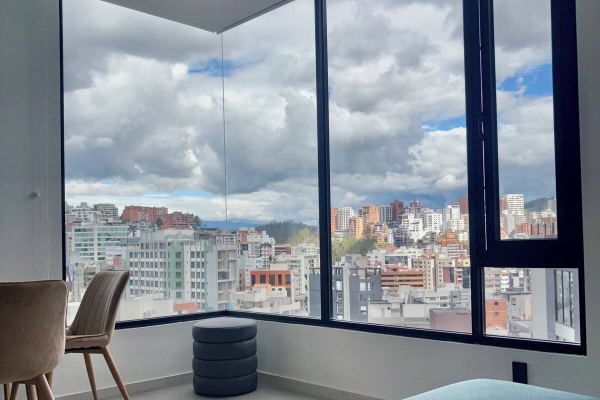 Una sala de estar moderna con un ventanal grande, una mesa redonda, una silla y un sofá.