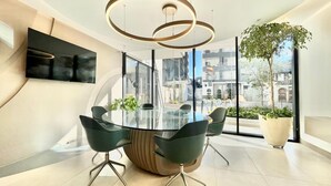 A modern conference room with a glass table, black chairs, and a unique circular ceiling light. - Harmony Luxury Apartments  (Quito)
