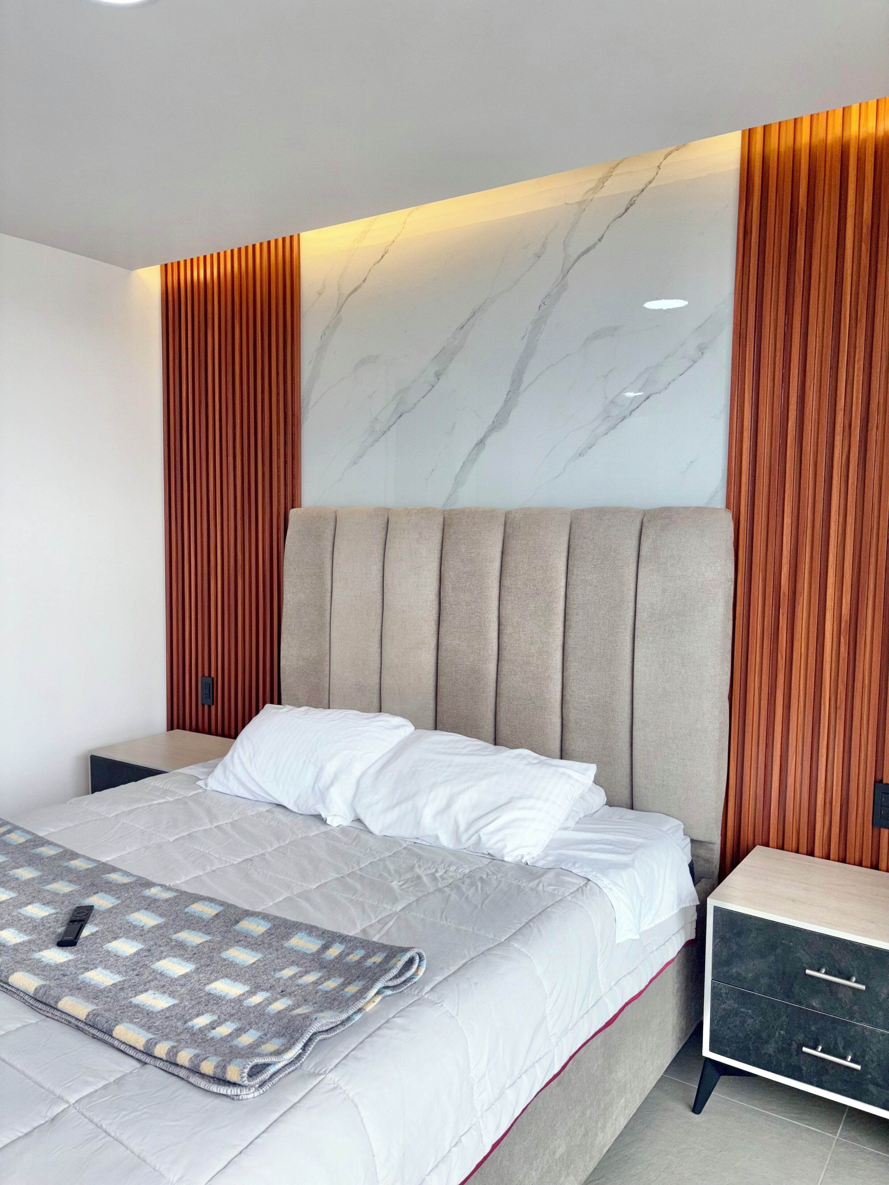 Una camera da letto moderna con un letto, comodini e una parete rivestita in legno.