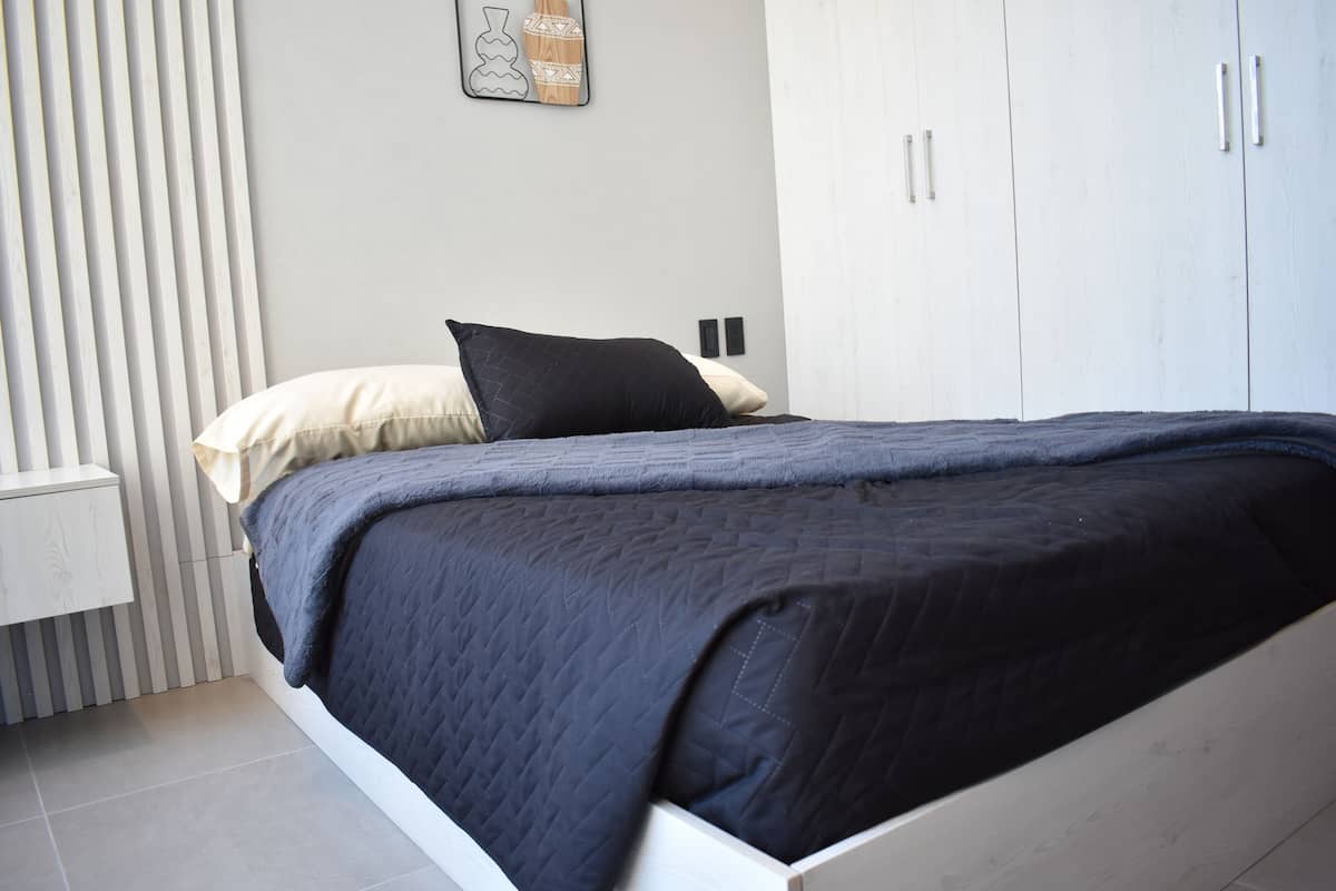 Un dormitorio moderno con cama, mesita de noche y armario.