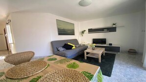 A modern living room with a sofa, a coffee table, and a TV. - Apt. ManRey 2A - Turquesa (Valle Gran Rey)