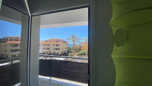 A balcony with a view of a residential area, including buildings and palm trees.