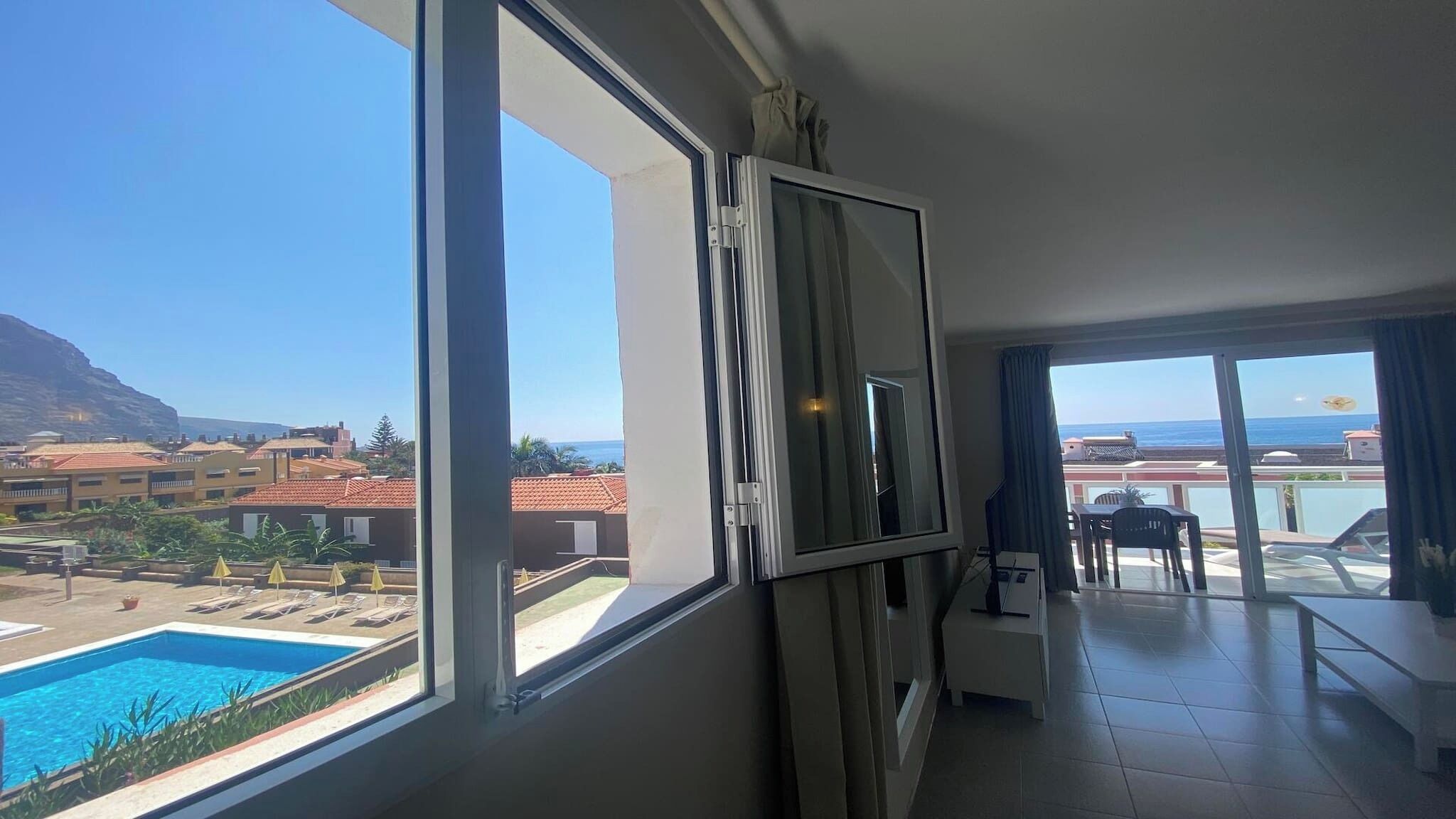 A balcony with a view of a swimming pool and a mountain.