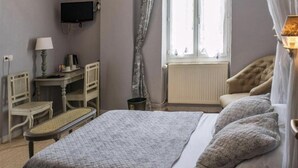 A bedroom with a bed, a desk, a chair, a television, and a window with curtains. - HOTEL DU PARC (Montélimar)