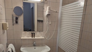 A bathroom with a sink, mirror, and shower. - HOTEL DU PARC (Montélimar)