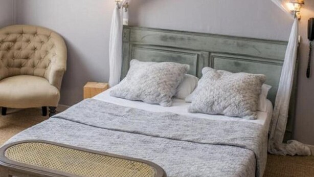 A bedroom with a bed, a chair, a bedside table, and a canopy bed. - HOTEL DU PARC (Montélimar)
