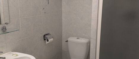 A small, clean bathroom with a toilet, sink, and a towel rack.