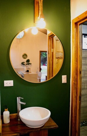 Ein Badezimmer mit einem runden Spiegel, einem weißen Waschbecken und einer Holzausstattung.