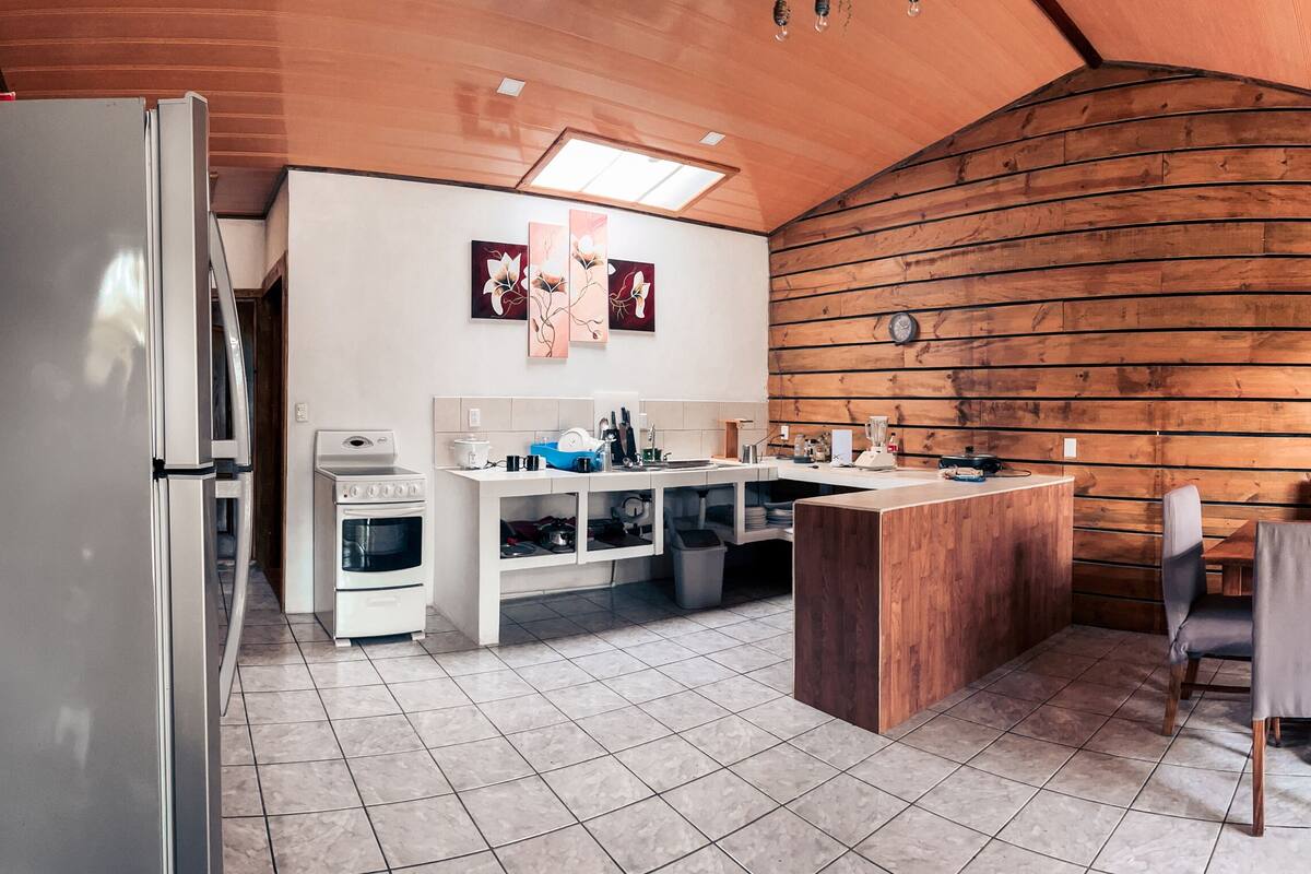 Eine Küche mit Holzvertäfelung, einem Kühlschrank, einem Herd und einem Essbereich mit Stühlen und einem Tisch.