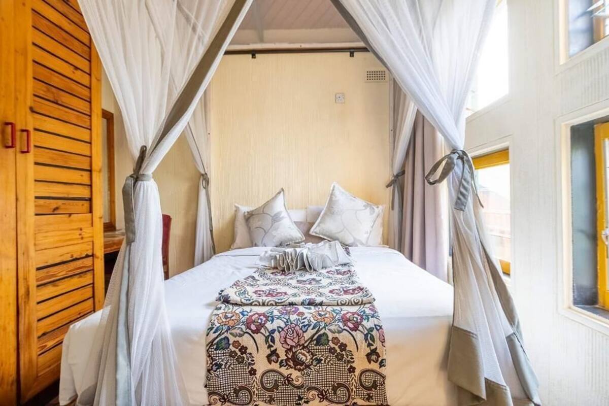 A bed with a canopy, white bedding, and a floral-patterned throw blanket.