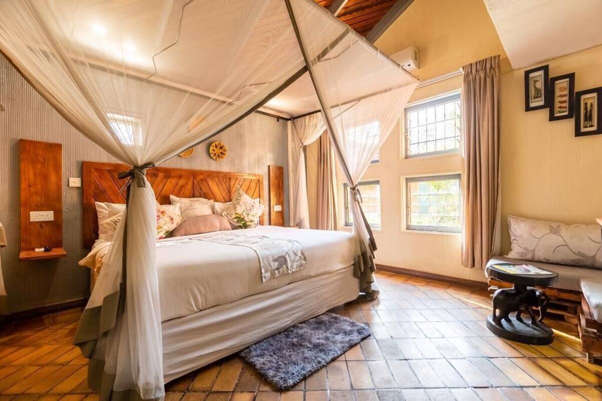 A bedroom with a canopy bed, a wooden headboard, a small table, and a sofa.