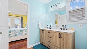 A bathroom with a wooden vanity, two sinks, and a window with blinds. - 4 BR Waterview Home- Pool- Gameroom- Sleeps 11 (North Myrtle Beach)