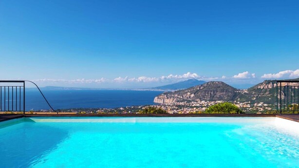 Piscina con vistas despejadas a un paisaje montañoso y al mar.