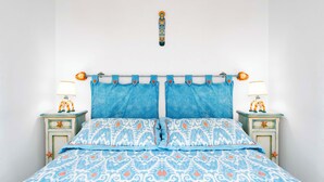 Una cama con colcha azul y blanca estampada, dos almohadas a juego y dos mesitas de noche con lámparas y decoraciones de estrellas de mar.