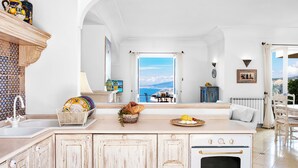 Una cocina amplia con vista al mar, un comedor con mesa y sillas, y una zona de estar acogedora con sofá.