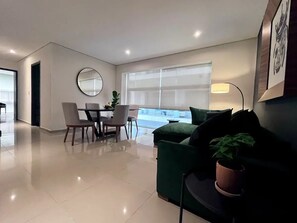 Relax in this stylish living room with a dining area, comfortable sofa, and large window offering a view of the outdoors.
