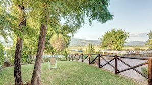 A grassy area with a wooden fence, trees, and a view of distant hills.