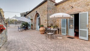A stone building with a patio area featuring outdoor seating and umbrellas.