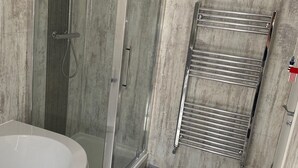 A bathroom with a glass-enclosed shower, a freestanding bathtub, and a towel rack.