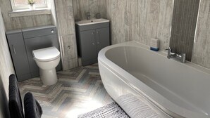 A modern bathroom with a freestanding bathtub, a toilet, and a sink. - Birdsong View - comfortable apartment in Amble (Amble)
