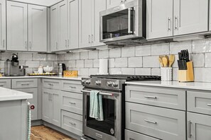 Una cocina moderna con armarios grises, una estufa de acero inoxidable, un microondas y una cafetera.